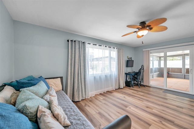 bedroom featuring ceiling fan, access to exterior, light hardwood / wood-style floors, and multiple windows