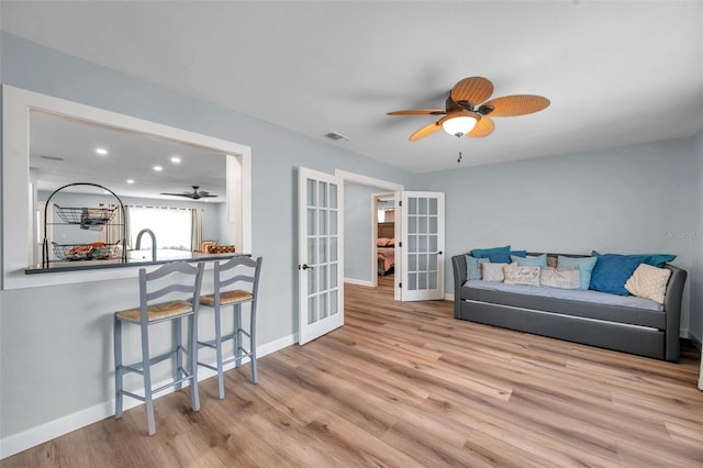 living room with french doors, ceiling fan, and light hardwood / wood-style flooring