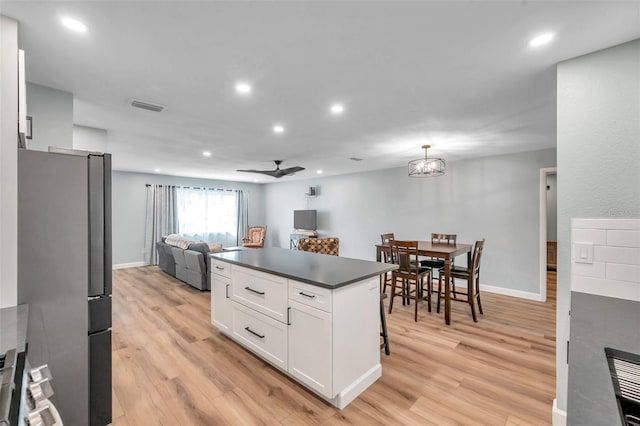 kitchen featuring stainless steel fridge, decorative light fixtures, white cabinets, and light hardwood / wood-style flooring