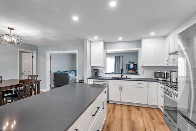 kitchen featuring pendant lighting, stainless steel appliances, sink, and white cabinets