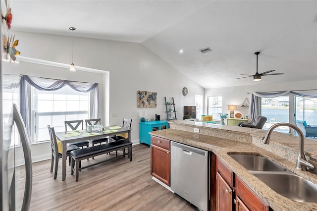 kitchen featuring plenty of natural light, dishwasher, sink, hanging light fixtures, and light stone countertops