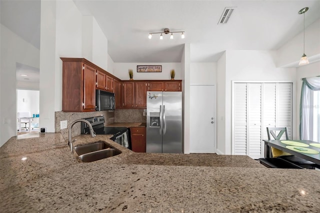 kitchen featuring sink, stainless steel appliances, tasteful backsplash, light stone counters, and decorative light fixtures