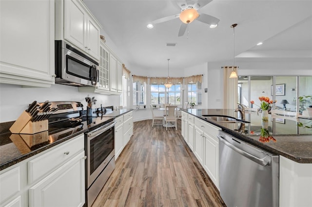 kitchen featuring pendant lighting, sink, dark stone countertops, white cabinets, and stainless steel appliances