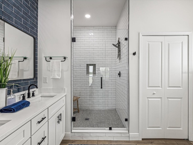 bathroom with hardwood / wood-style flooring, vanity, and a shower with shower door