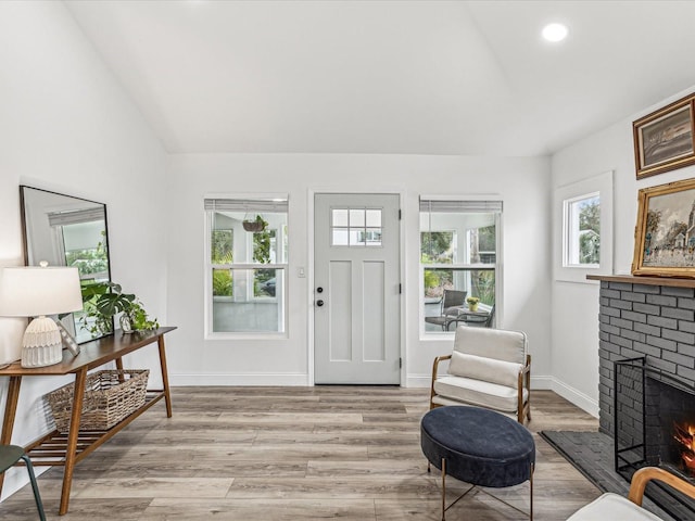 entryway featuring lofted ceiling, a fireplace, and light wood-type flooring