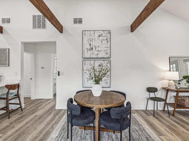 dining room featuring lofted ceiling with beams and light wood-type flooring