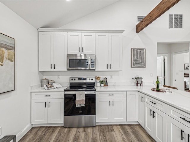 kitchen featuring vaulted ceiling, appliances with stainless steel finishes, white cabinets, and light wood-type flooring