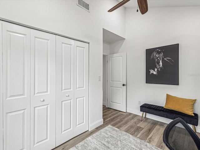 living area with hardwood / wood-style floors, beam ceiling, ceiling fan, and a high ceiling