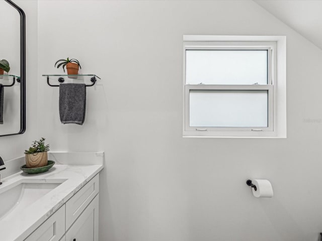 bathroom featuring vanity, a wealth of natural light, and vaulted ceiling