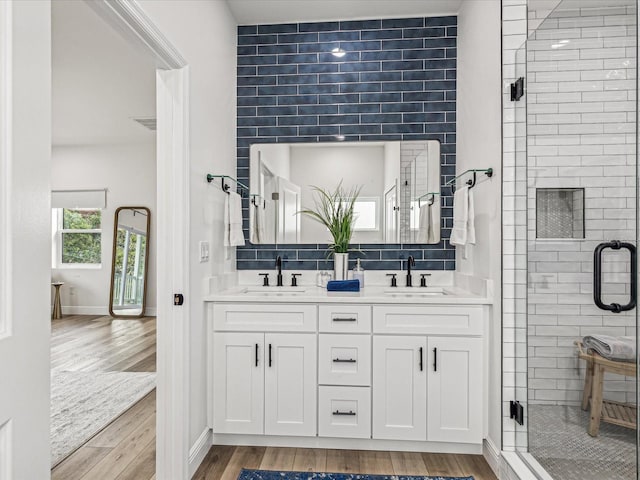 bathroom with wood-type flooring, vanity, backsplash, and walk in shower