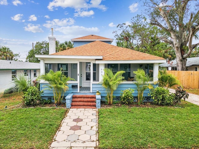 bungalow-style house with a front lawn and a sunroom