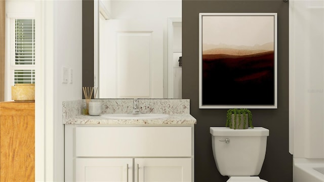 bathroom featuring vanity, a tub to relax in, and toilet