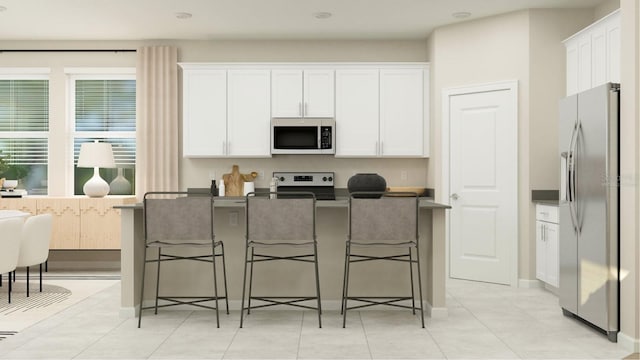 kitchen featuring white cabinetry, stainless steel appliances, and a kitchen bar