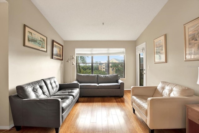 living area with baseboards, vaulted ceiling, and light wood finished floors