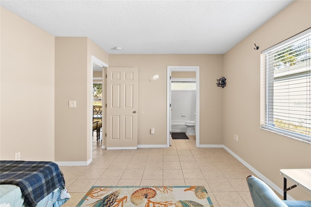 bedroom featuring light tile patterned floors, a textured ceiling, and ensuite bathroom