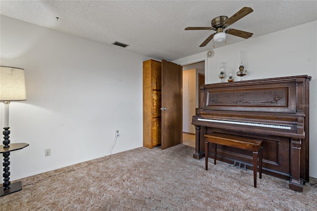 sitting room featuring ceiling fan, light colored carpet, and a textured ceiling