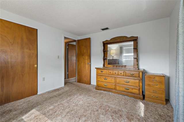 bedroom with a closet, light carpet, and a textured ceiling