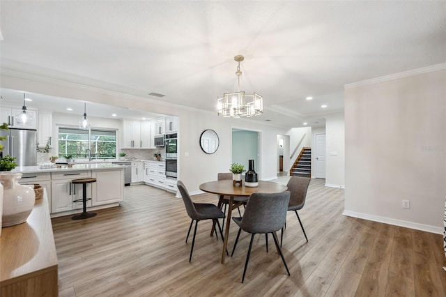 dining space featuring ornamental molding, sink, a notable chandelier, and light hardwood / wood-style floors