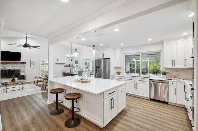 kitchen featuring white cabinetry, appliances with stainless steel finishes, a kitchen breakfast bar, a kitchen island, and pendant lighting