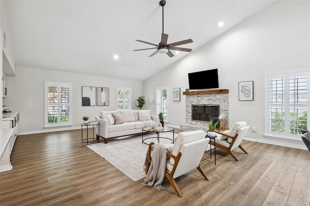 living room featuring a stone fireplace, a wealth of natural light, and light wood-type flooring