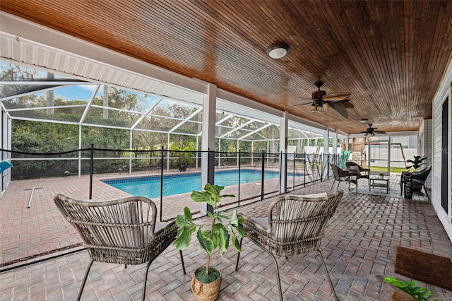 view of swimming pool with outdoor lounge area, a patio, ceiling fan, and glass enclosure