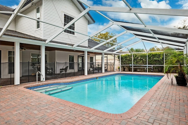 view of swimming pool with a patio, ceiling fan, and glass enclosure