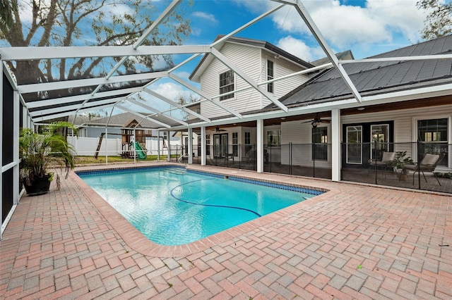 view of swimming pool with ceiling fan, glass enclosure, a playground, and a patio