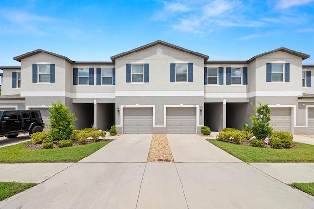 multi unit property with a garage, driveway, and stucco siding