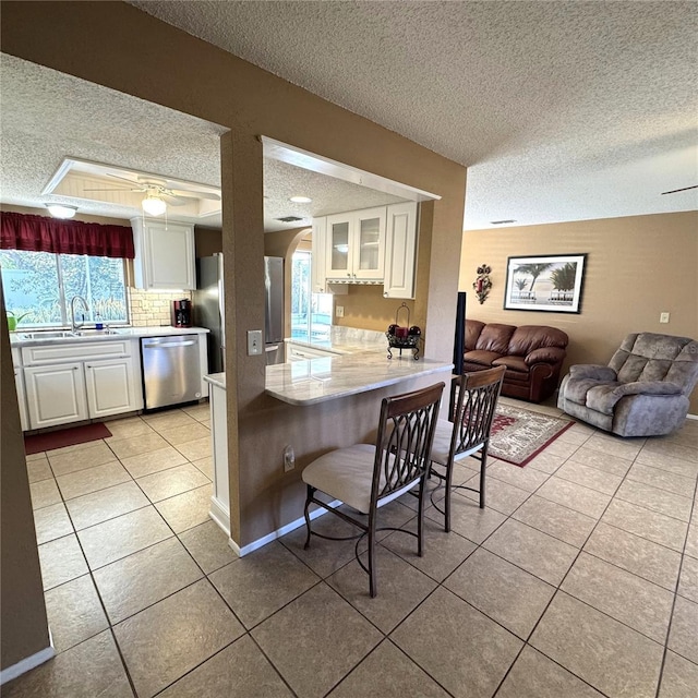 kitchen with stainless steel dishwasher, kitchen peninsula, white cabinets, and refrigerator