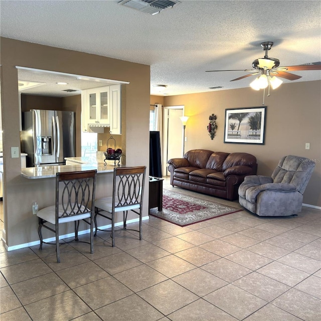 living room featuring light tile patterned floors, a textured ceiling, and ceiling fan