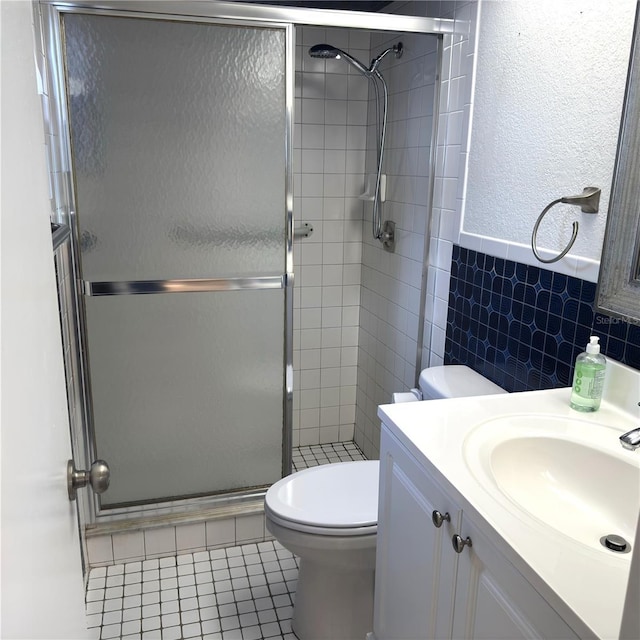 bathroom featuring walk in shower, tile patterned floors, toilet, tile walls, and vanity