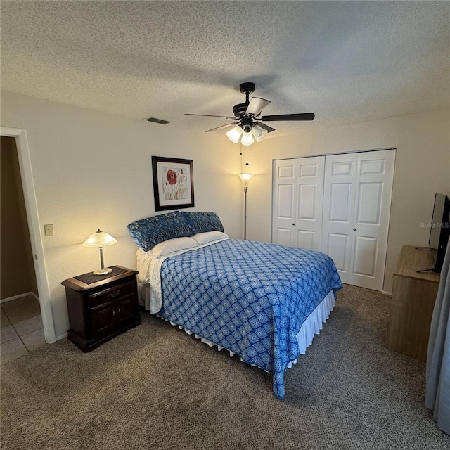 carpeted bedroom with ceiling fan, a textured ceiling, and a closet