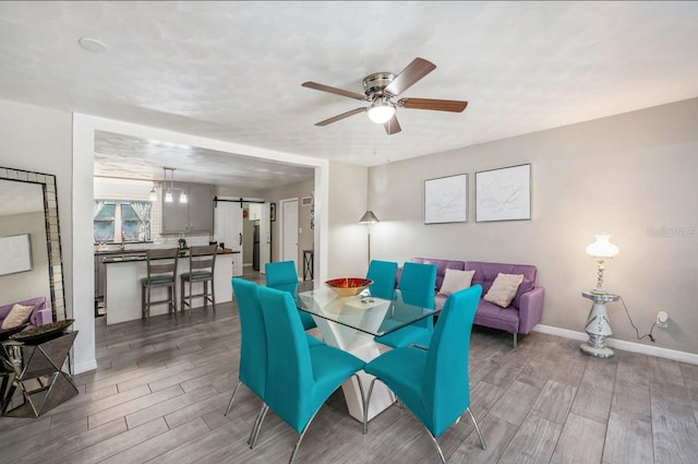 dining area with a barn door and ceiling fan