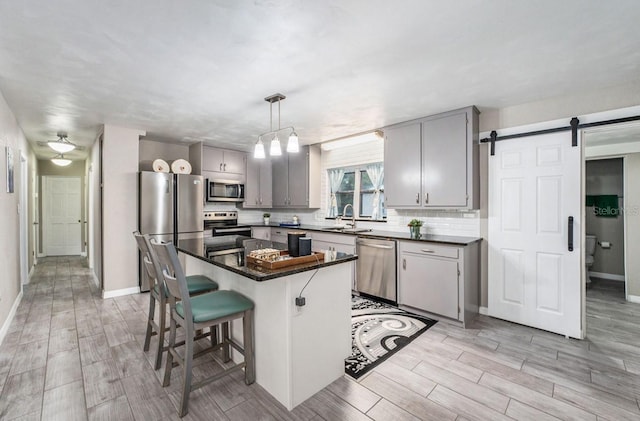 kitchen featuring pendant lighting, sink, gray cabinets, appliances with stainless steel finishes, and a kitchen island