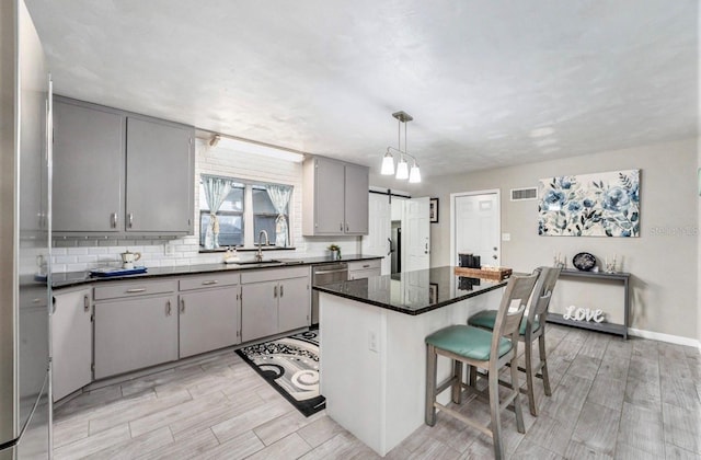 kitchen with pendant lighting, a center island, a barn door, and gray cabinets