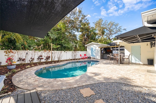 view of swimming pool featuring a shed and a patio