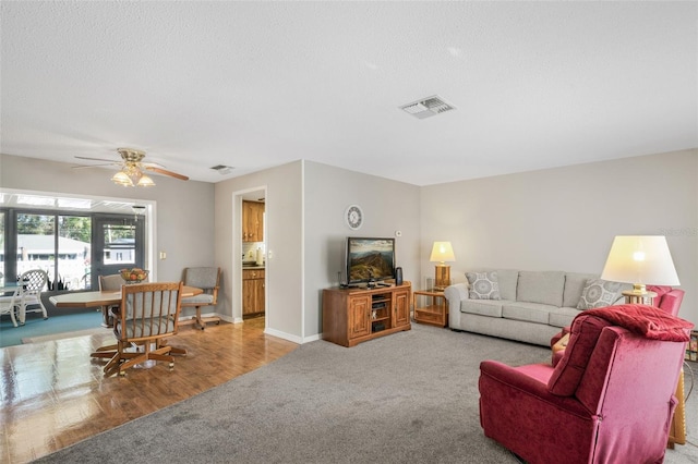 carpeted living room featuring a textured ceiling and ceiling fan