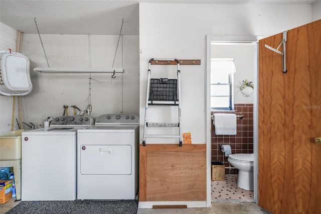 laundry area featuring tile walls and washing machine and dryer