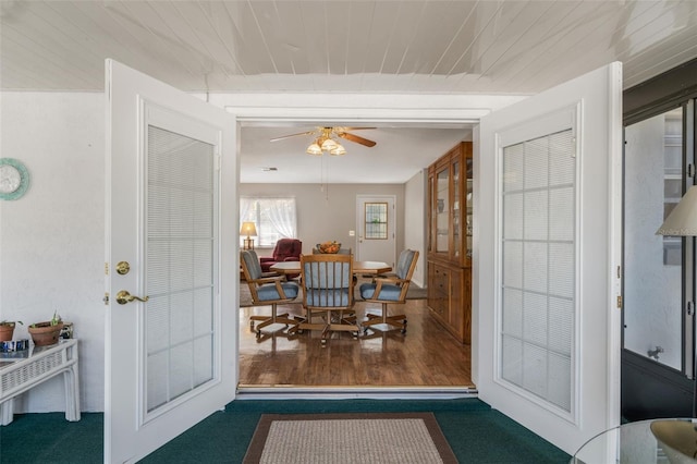 dining space featuring dark wood-type flooring, ceiling fan, and wooden ceiling