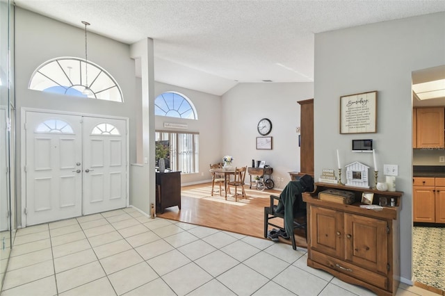 tiled entrance foyer with high vaulted ceiling and a textured ceiling