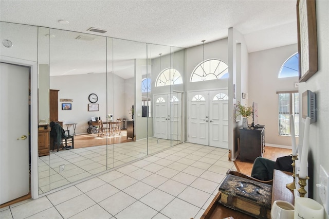 tiled entryway featuring high vaulted ceiling and a textured ceiling