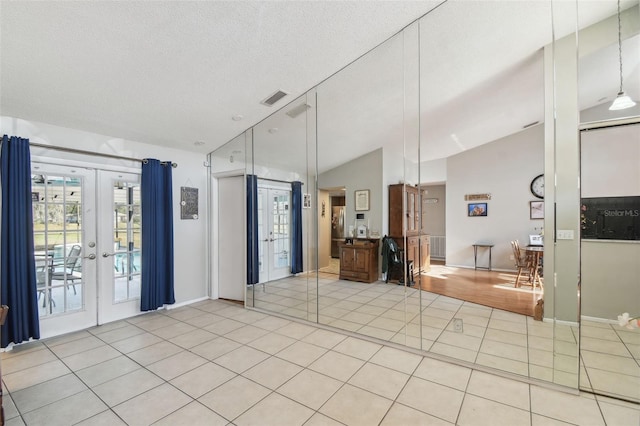 bathroom featuring vaulted ceiling, tile patterned floors, french doors, and a textured ceiling