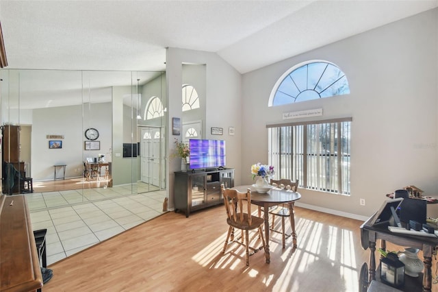 dining room featuring hardwood / wood-style floors, high vaulted ceiling, and a textured ceiling