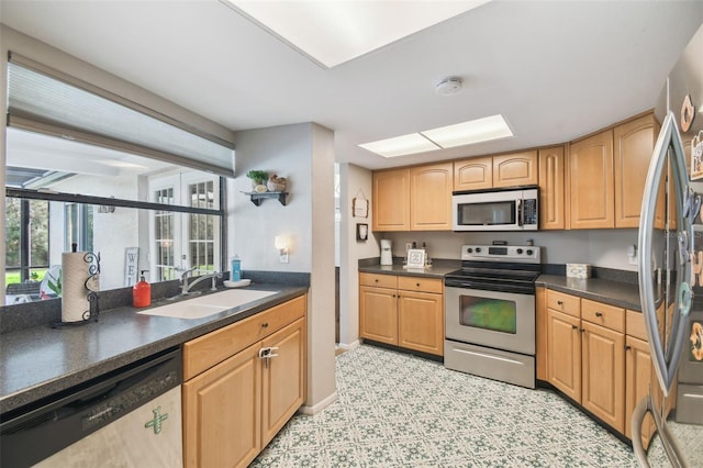 kitchen featuring sink, a skylight, and appliances with stainless steel finishes