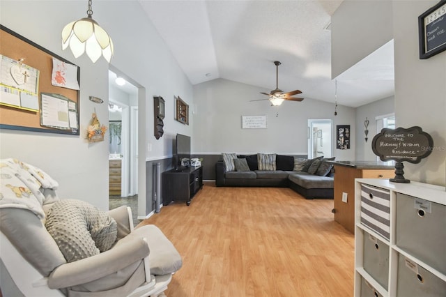 living room with ceiling fan, vaulted ceiling, and light wood-type flooring