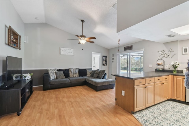 living room featuring ceiling fan, lofted ceiling, and light hardwood / wood-style flooring