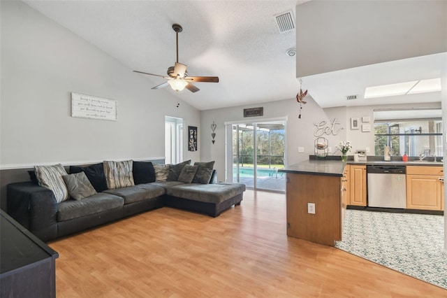 living room featuring a textured ceiling, light hardwood / wood-style flooring, ceiling fan, and vaulted ceiling