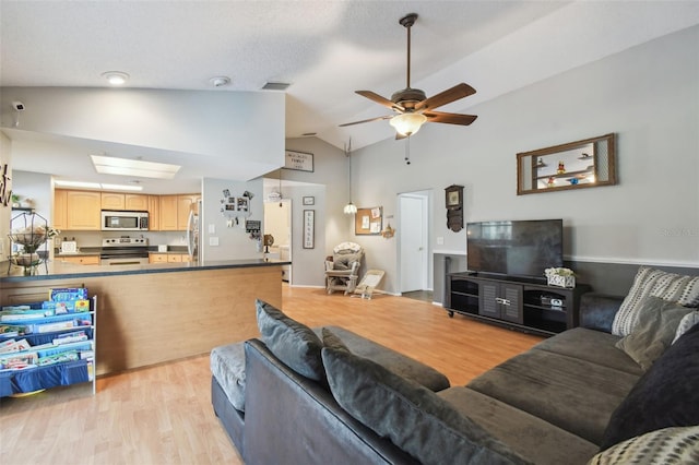 living room with lofted ceiling with skylight, a textured ceiling, ceiling fan, and light hardwood / wood-style floors