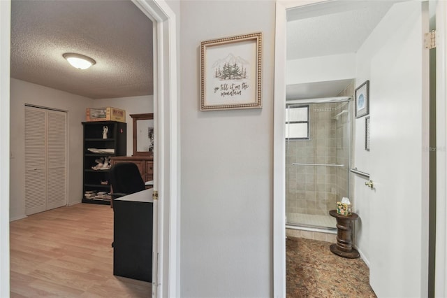 bathroom featuring hardwood / wood-style floors, a shower with door, and a textured ceiling