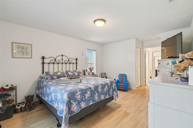 bedroom featuring a textured ceiling and light hardwood / wood-style flooring